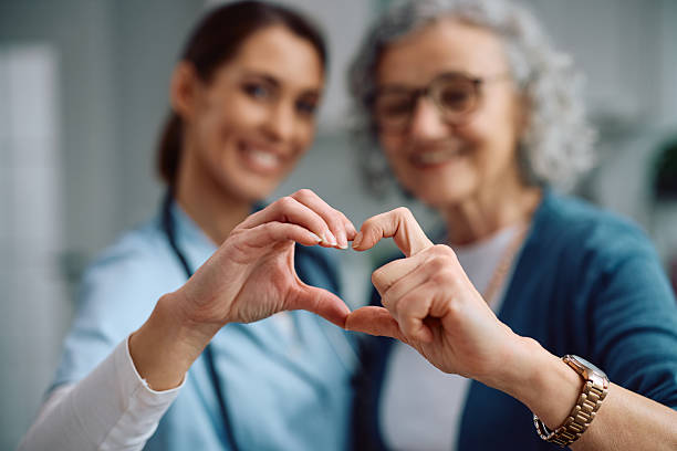 istockphoto-2207786960-612x612 Close up of nurse and senior woman making heart shape with hands during a home visit.